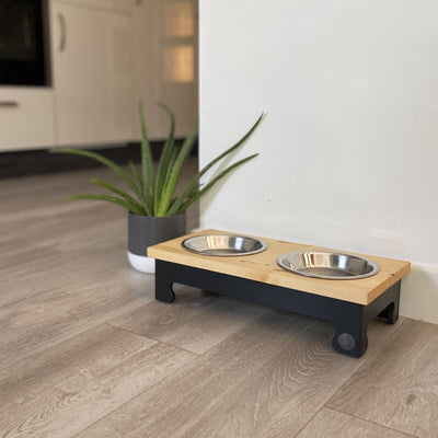 A double-bowl raised feeding stand with a pine top in charcoal black.
