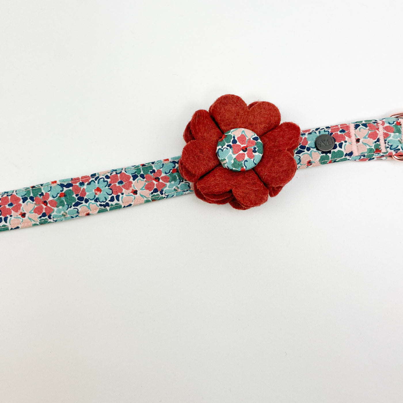 Dog collar flower accessory in burnt umber felt with a Liberty fabric button centre, shown on  a Liberty floral print dog collar.