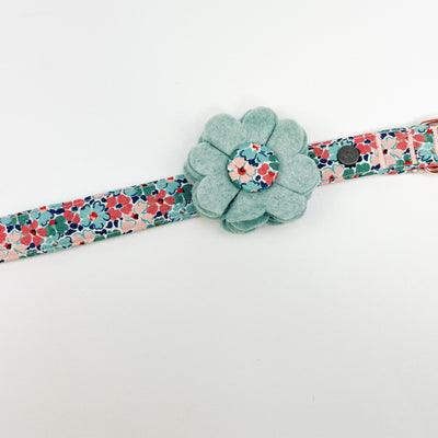 Dog collar flower accessory in soft teal felt with a Liberty fabric button shown on a Liberty floral collar.