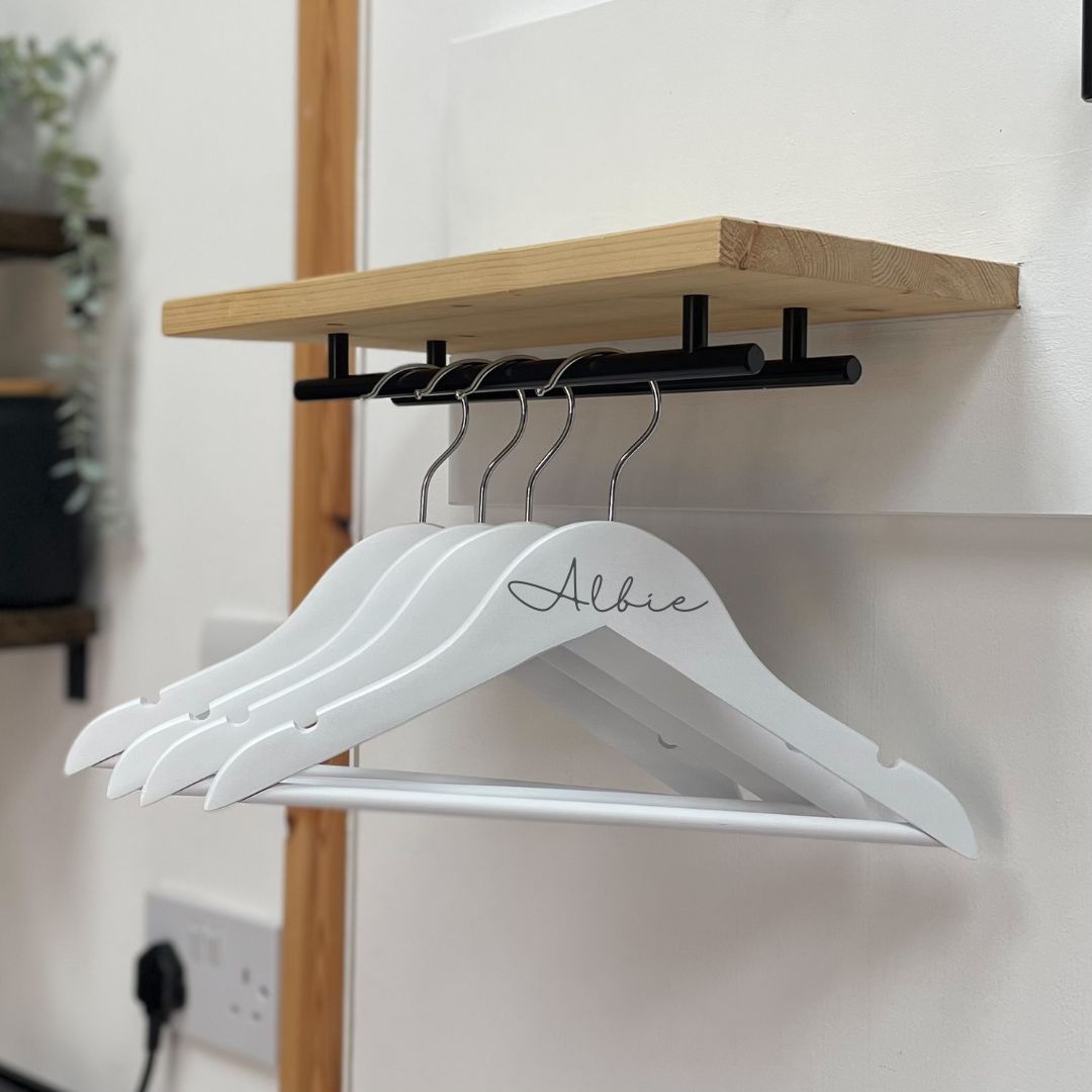 Set of four white, wooden personalised hangers. hang from a dog lead station rail