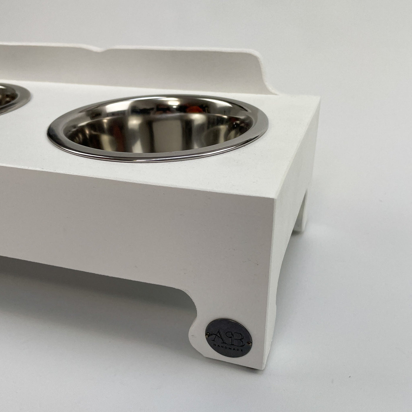 Stainless steel dog bowl in a white raised feeder stand.