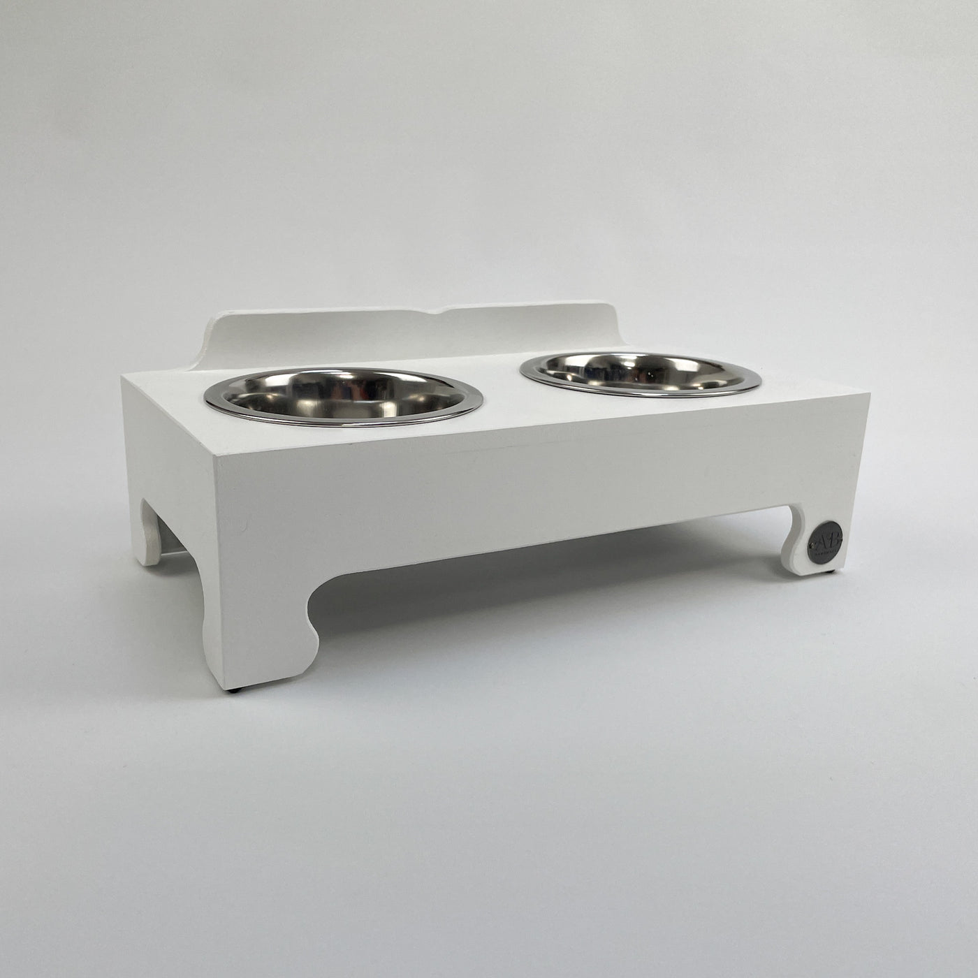 Small raised dog bowl feeding stand in white with stainless steel food dishes.
