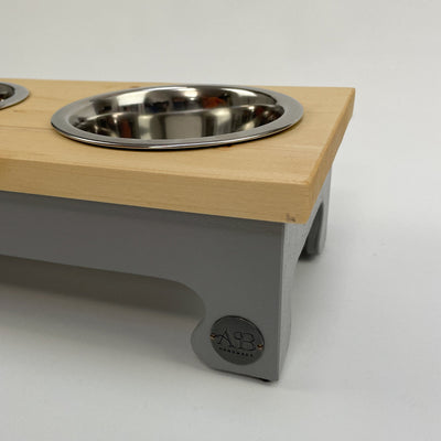 Grey feeding station with pine top and stainless steel bowls.