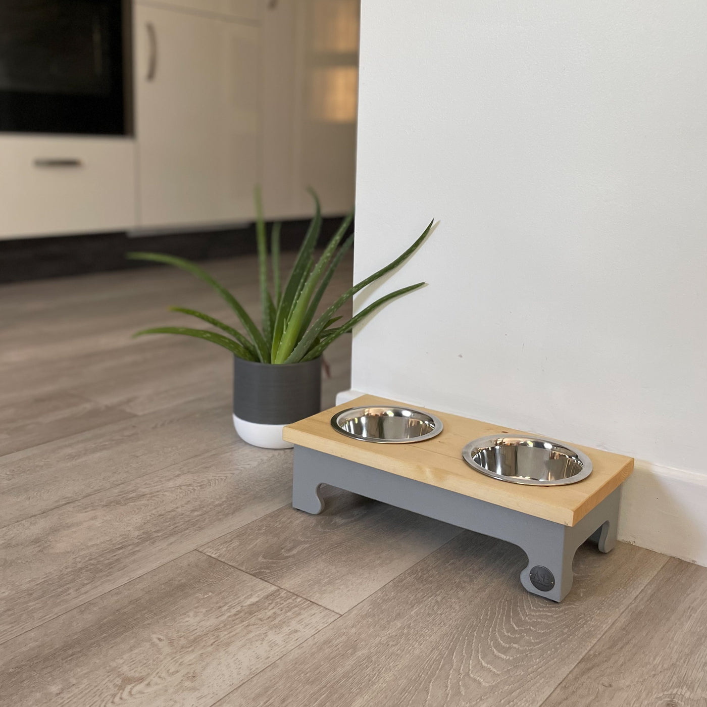 A double-bowl pet feeder stand with natural pine top in grey.