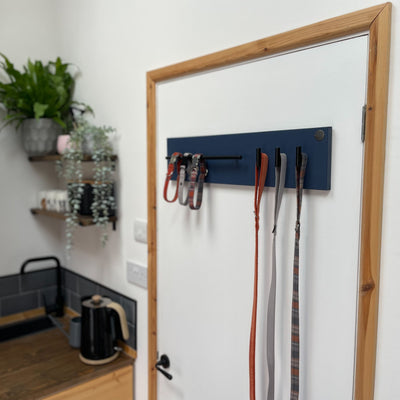 Navy dog lead station with organised dog walking accessories hung from fittings.