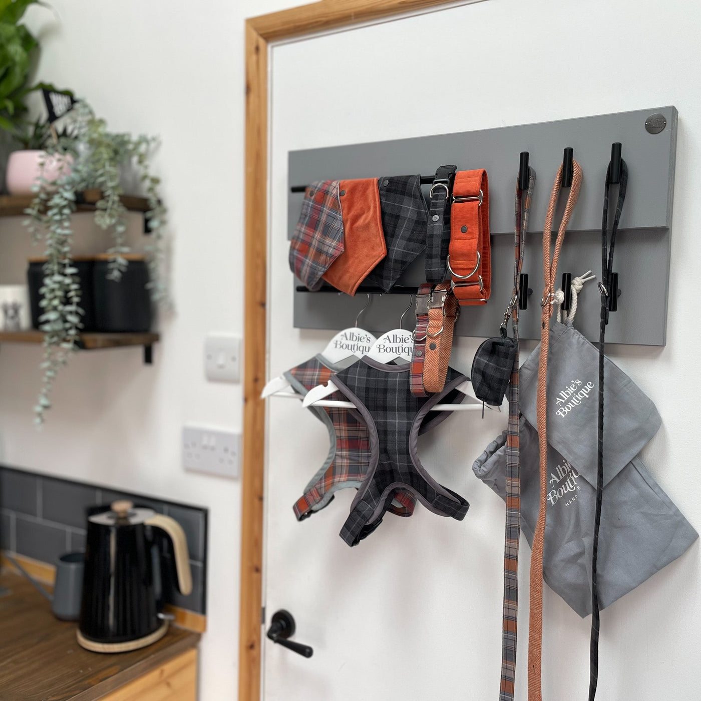 Dog walking accessories hang organised from a wall-hung large, grey, double-rail lead station with 6 hooks. 