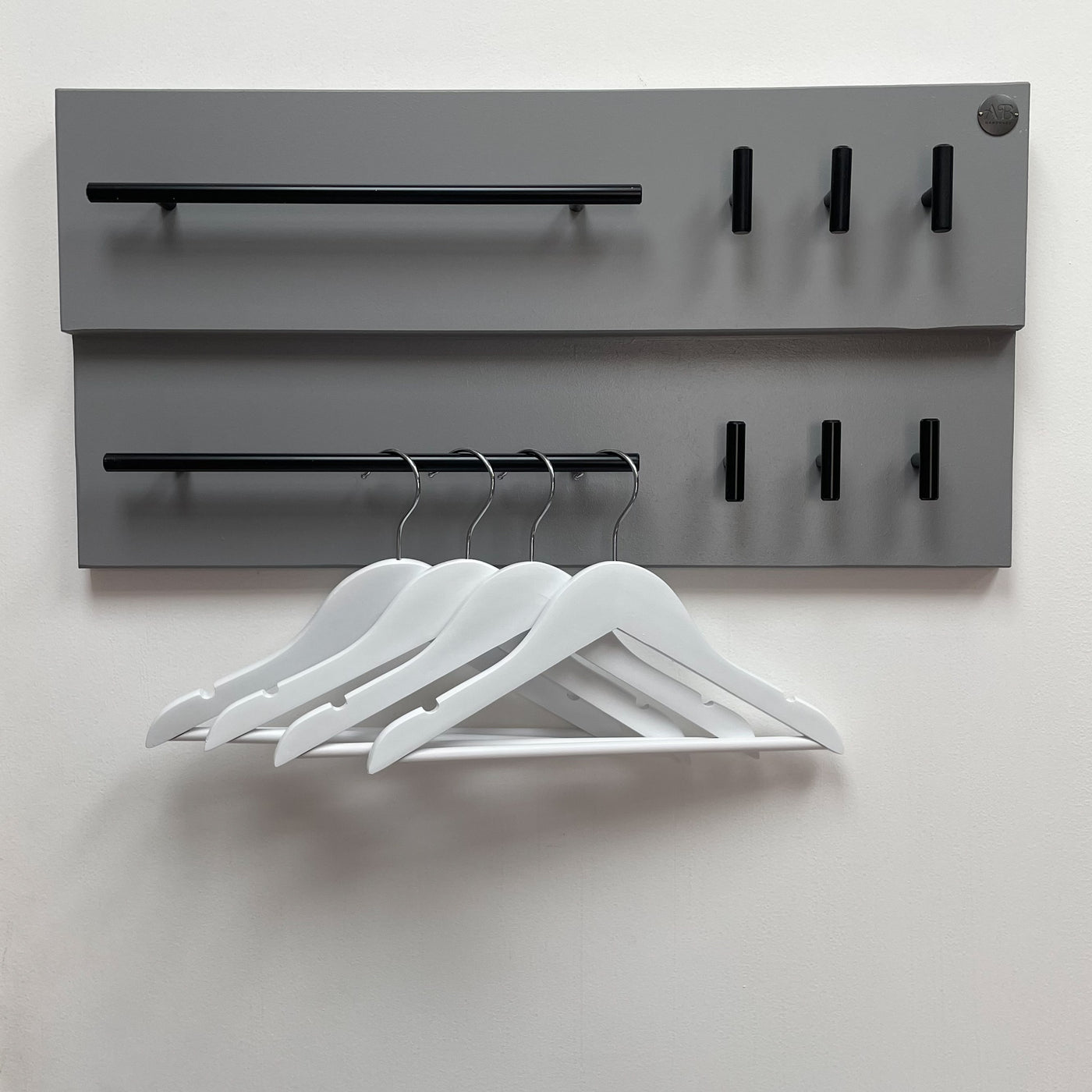 Set of four white, wooden hangers hung on a lead station.